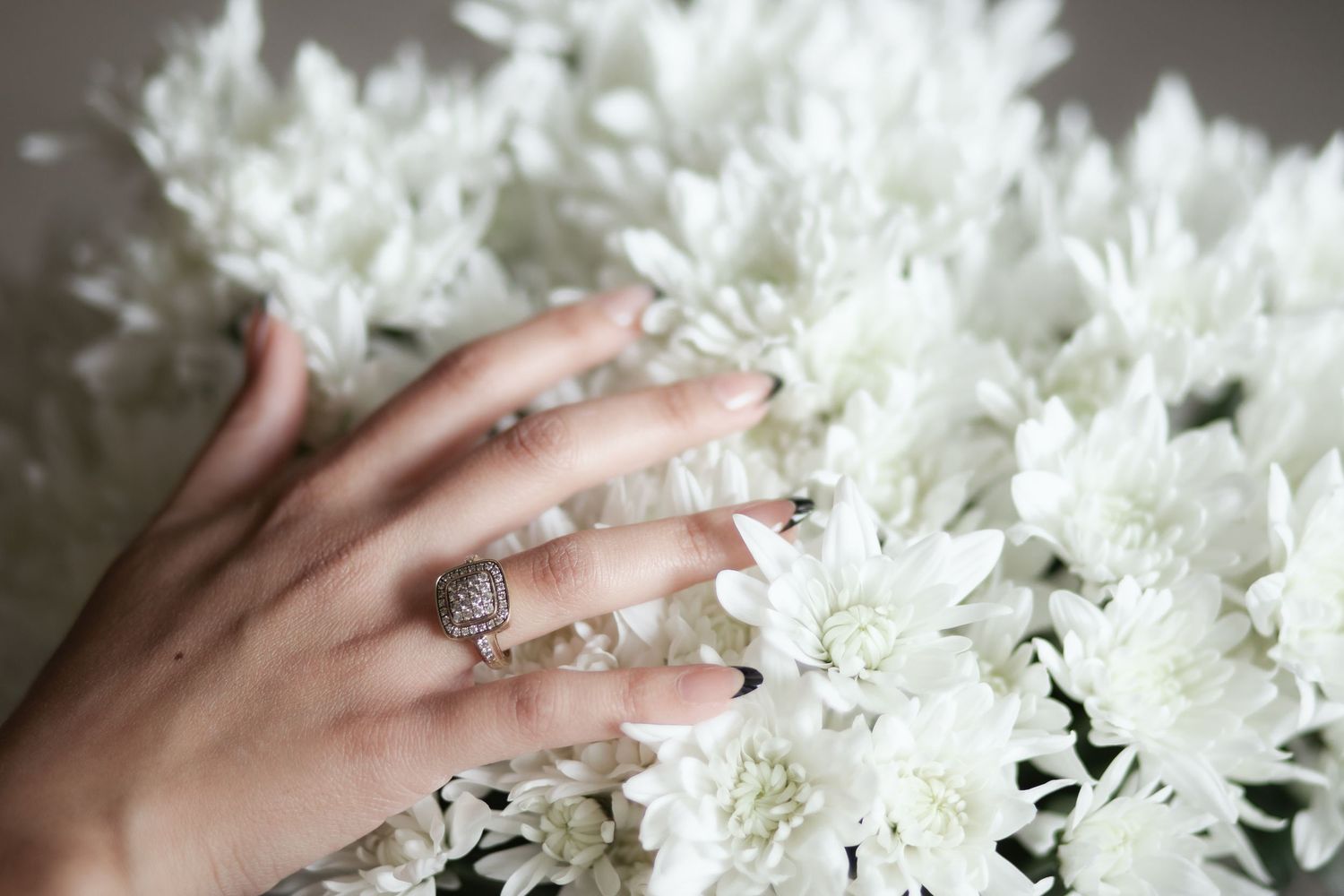 Brides hand showcasing ring over white flowers in Miami