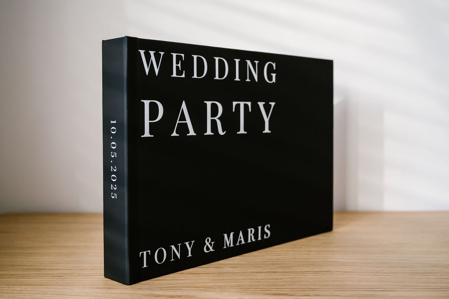 White wedding photo album box with ribbon bow, embossed with Our Love Story text, displayed on wooden surface.
