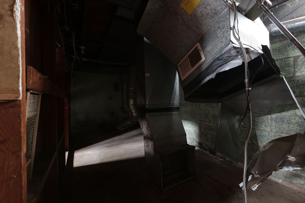 Industrial HVAC ductwork and ventilation system components in a dark mechanical room.
