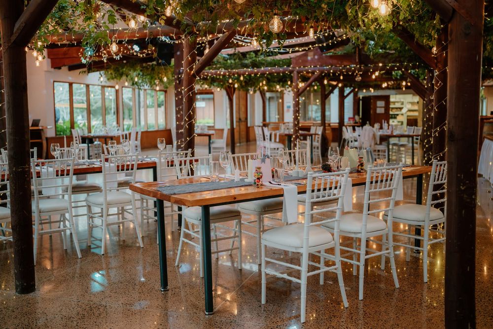 A rustic outdoor wedding reception venue decorated with string lights and white chairs at dusk.