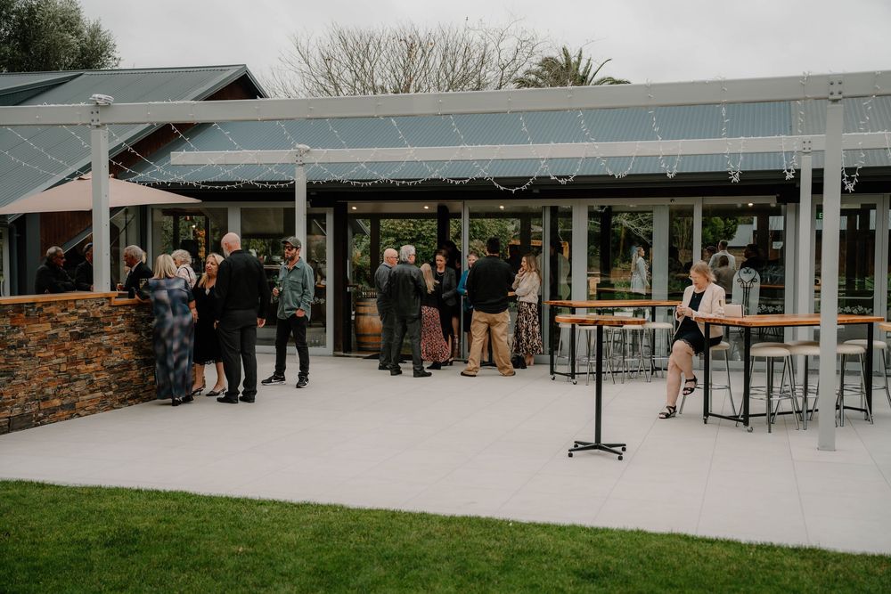 Modern outdoor event venue with covered pavilion area and brick accents set against natural landscaping.