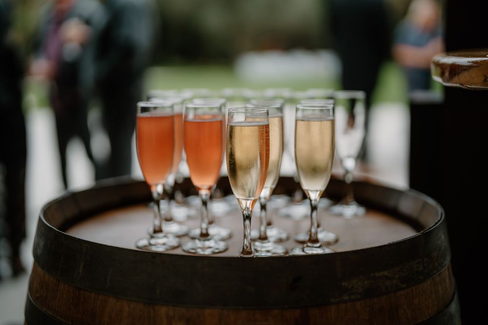Multiple glasses of champagne are carried on round serving trays during an elegant event.