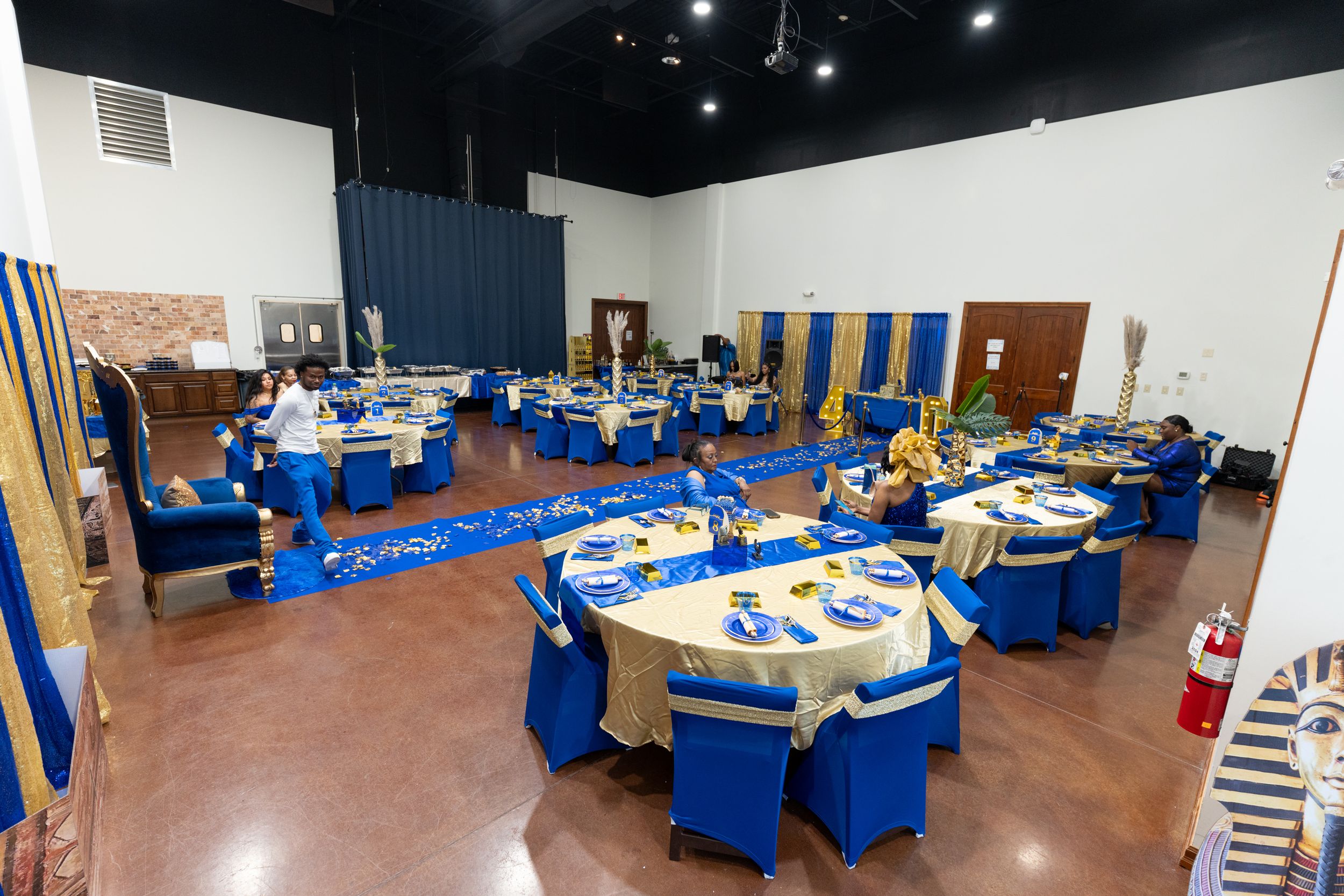 Elegant banquet hall with blue and gold table settings arranged for a formal event or celebration.