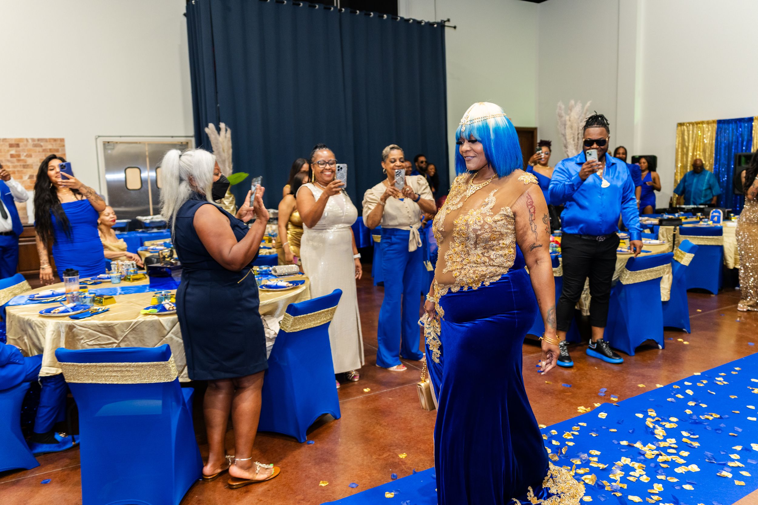 Elegant blue and gold formal event with guests in gowns celebrating in a decorated banquet hall.