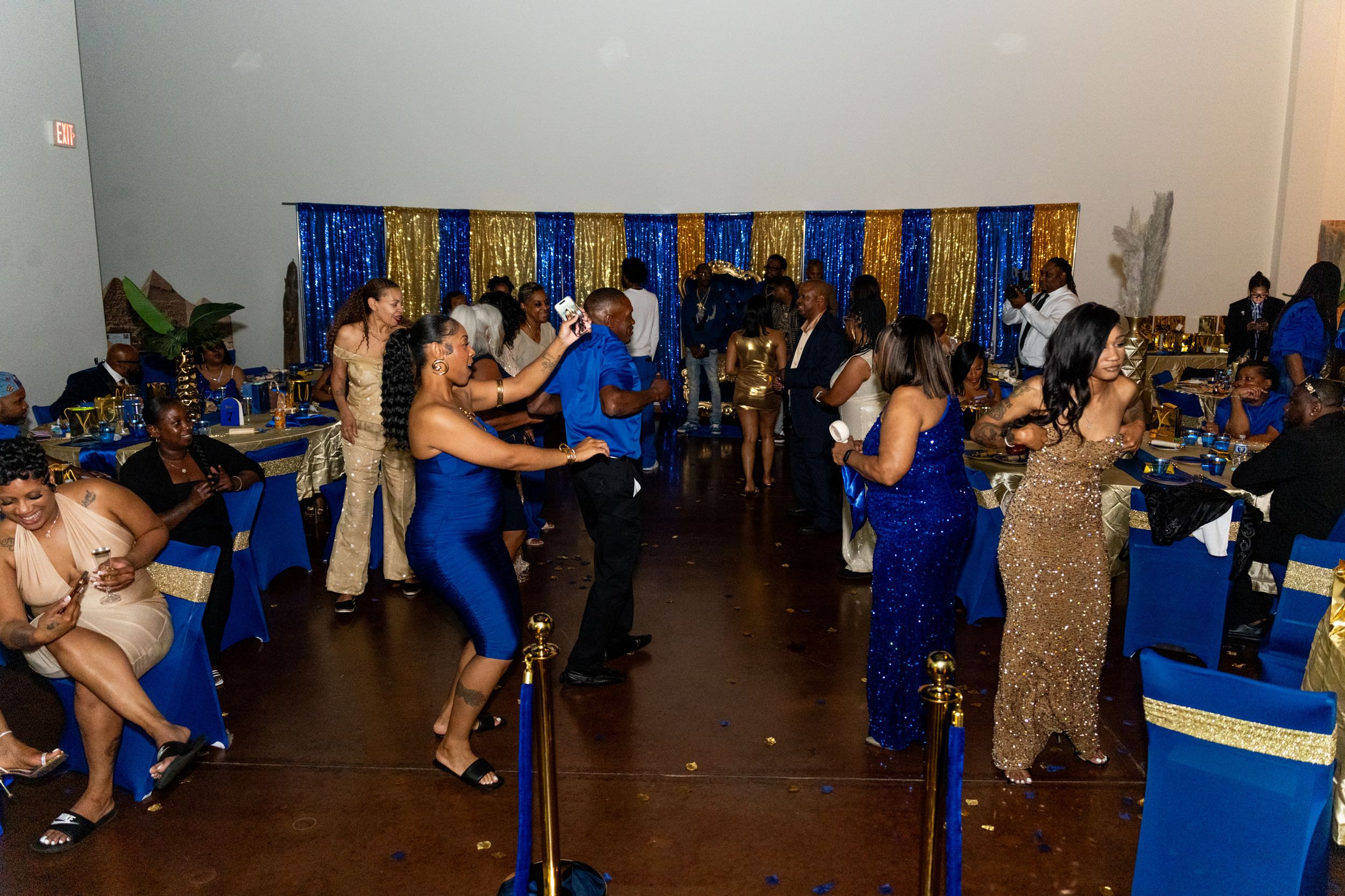 Guests dancing and socializing at an elegant blue and gold themed gala event with decorated tables.