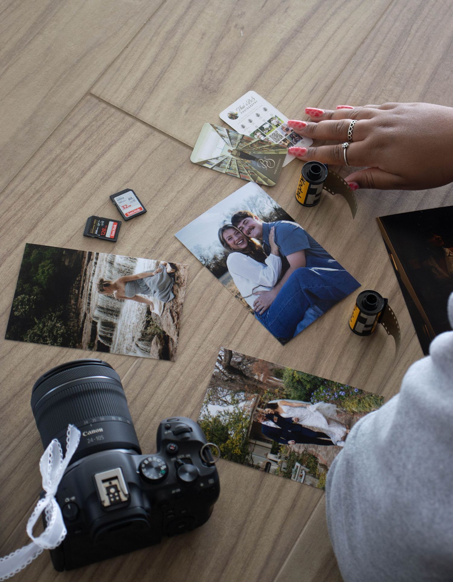 Canon camera, film rolls, and printed couple photos arranged on a wooden surface.