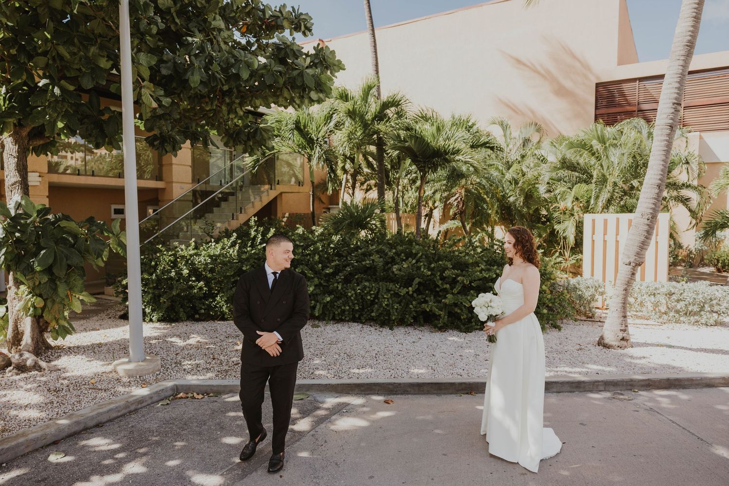Bride and groom share a first look moment outdoors near palm trees at divi Tamarijn Aruba wedding venue.