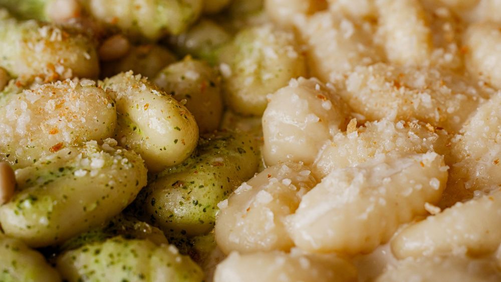 Close-up of pesto gnocchi with pine nuts next to butter-toasted gnocchi with breadcrumbs.