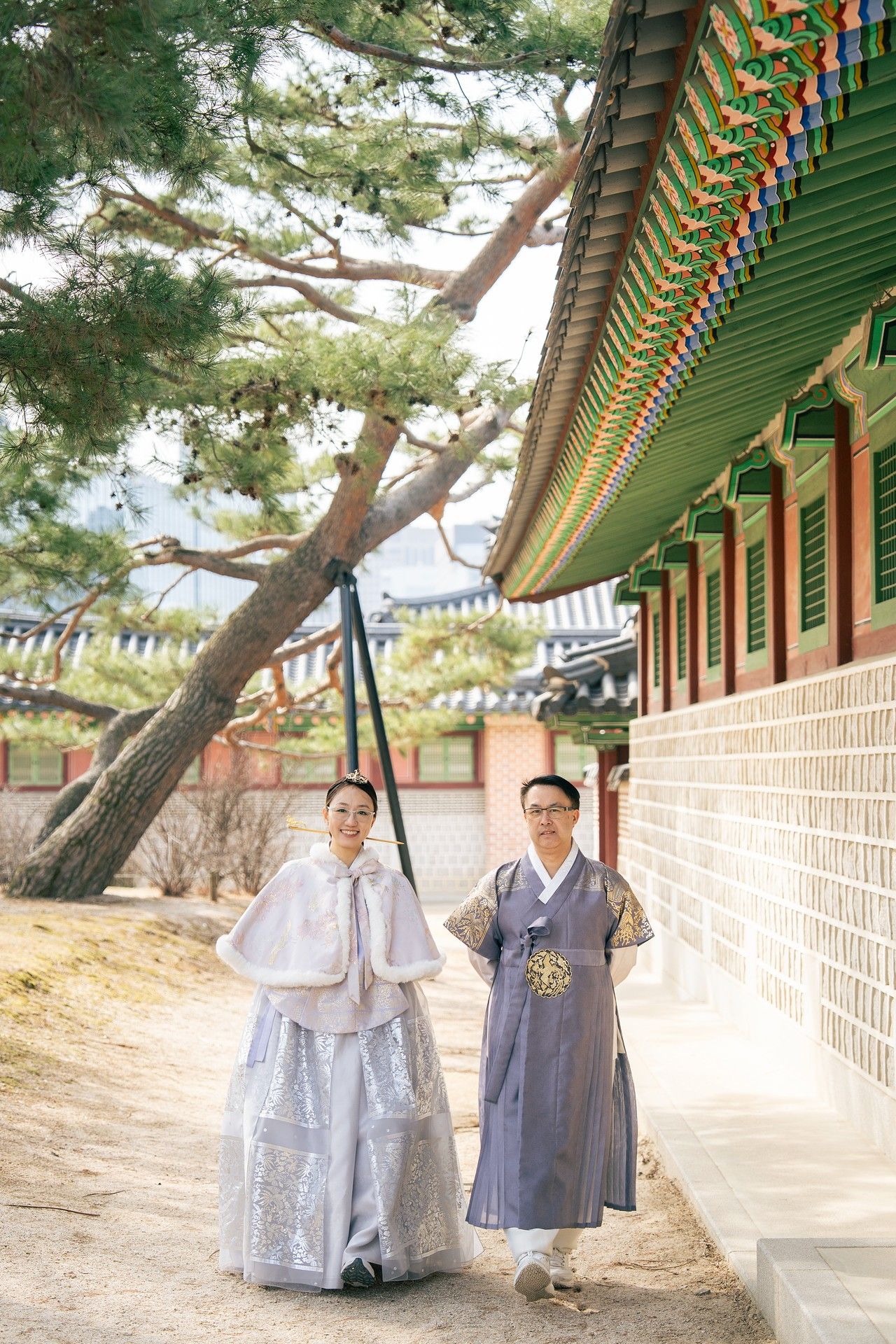 Couple wearing traditional Korean hanbok attire walking along a palace corridor at Gyeongbokgung, Seoul.