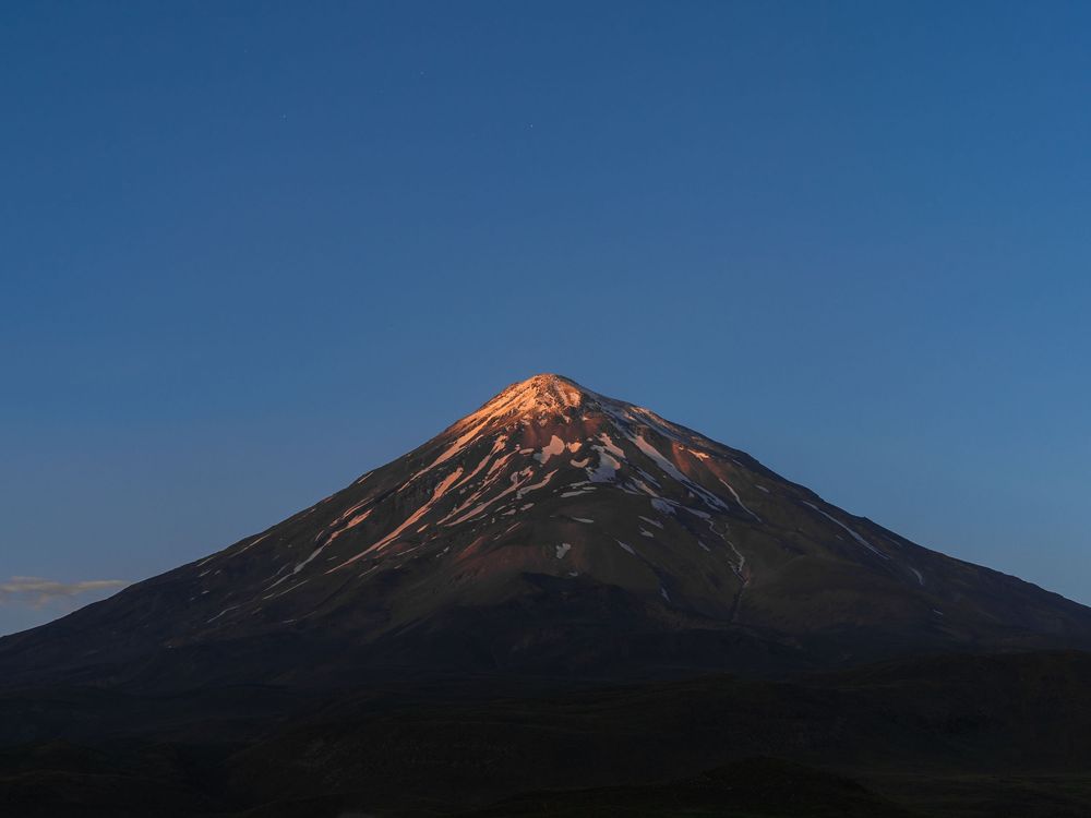 Mount Damavand, Iran, glowing in alpenglow at twilight.