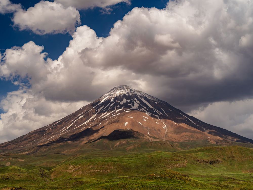 Mount Damavand above Dashte Lar plain, Iran, with snow-streaked slopes and green foothills.