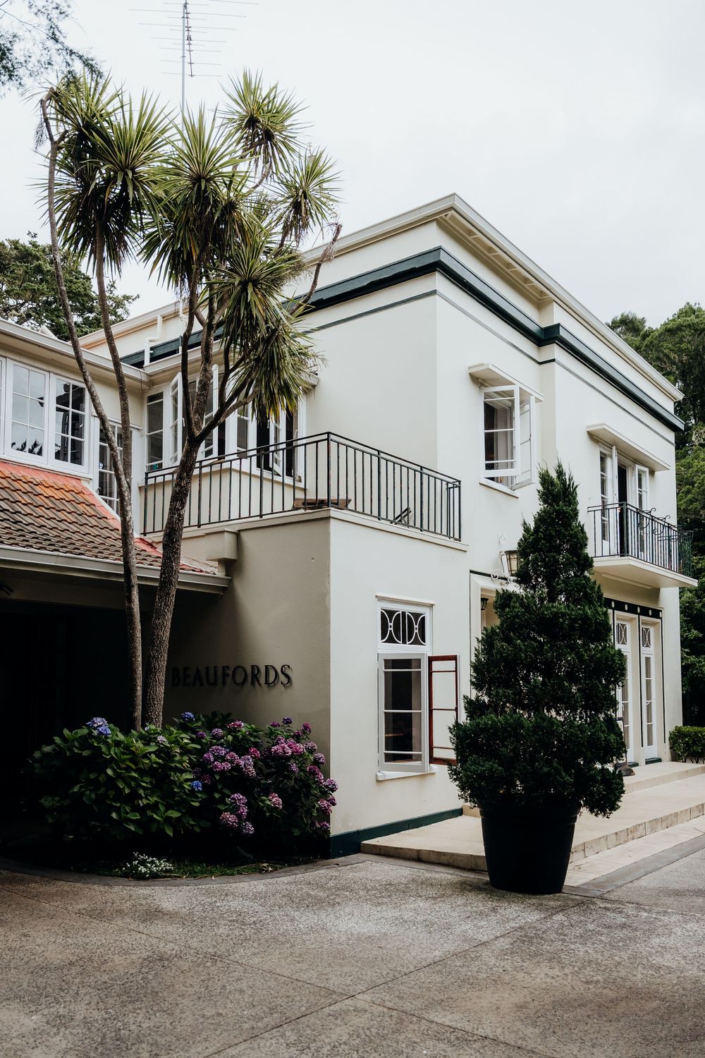 Exterior of Beaufords venue, a white two-story building surrounded by palm trees and hydrangeas.