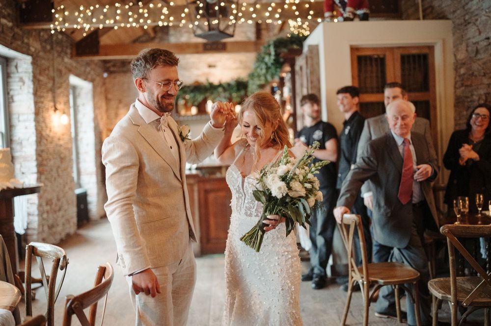 Bride and groom sharing first dance in a rustic stone venue decorated with fairy lights.