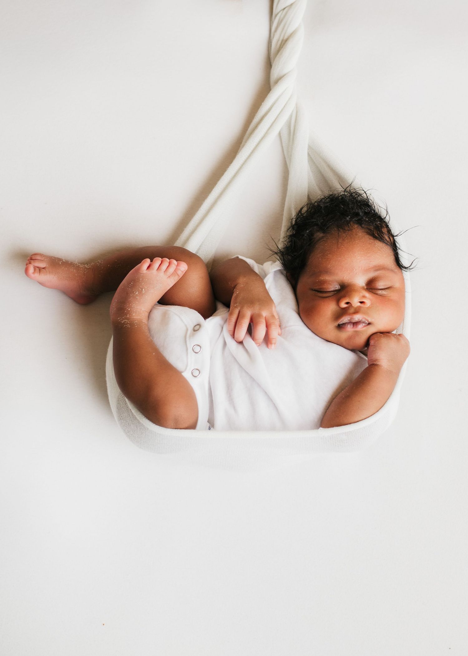 Sleeping newborn baby lying in a white wrap on a light background