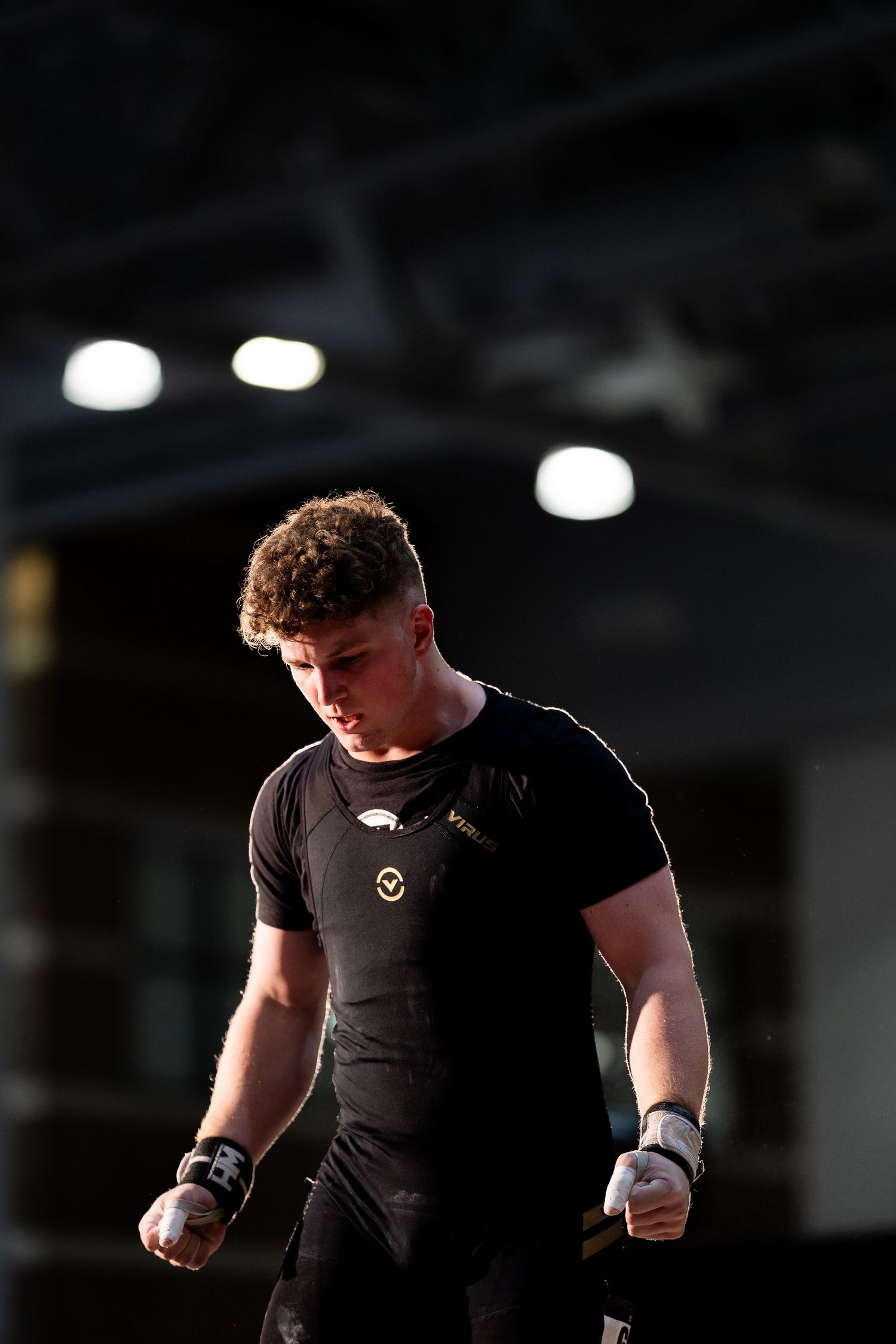 An athlete in black compression gear preparing for competition under dramatic lighting.
