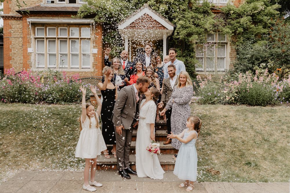 Romantic couple and wedding guests gather outside Artington House Guildford Registry building for the big confetti shower exit.