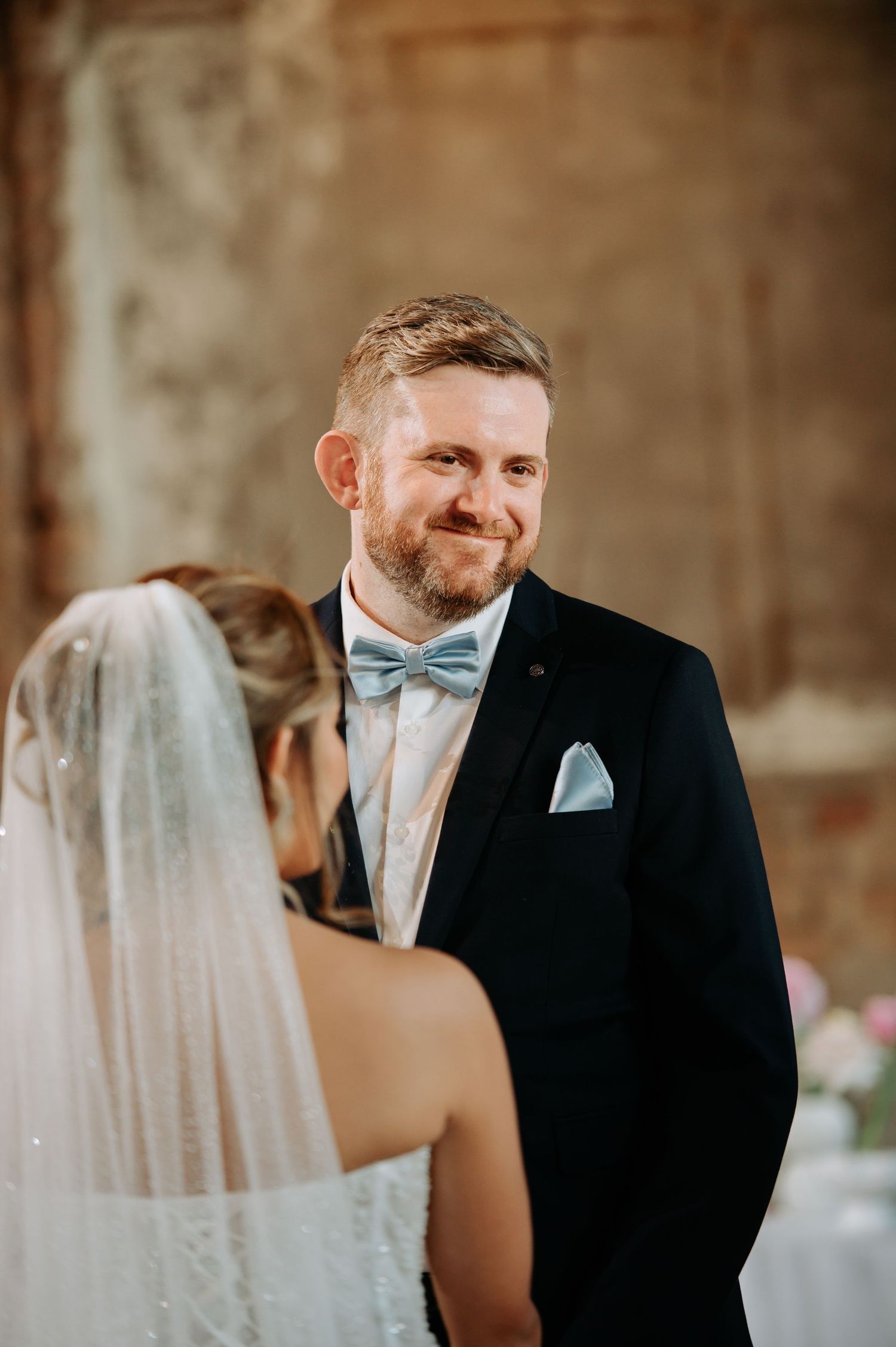 Emotional wedding ceremony moment with couple exchanging vows under brick archway.