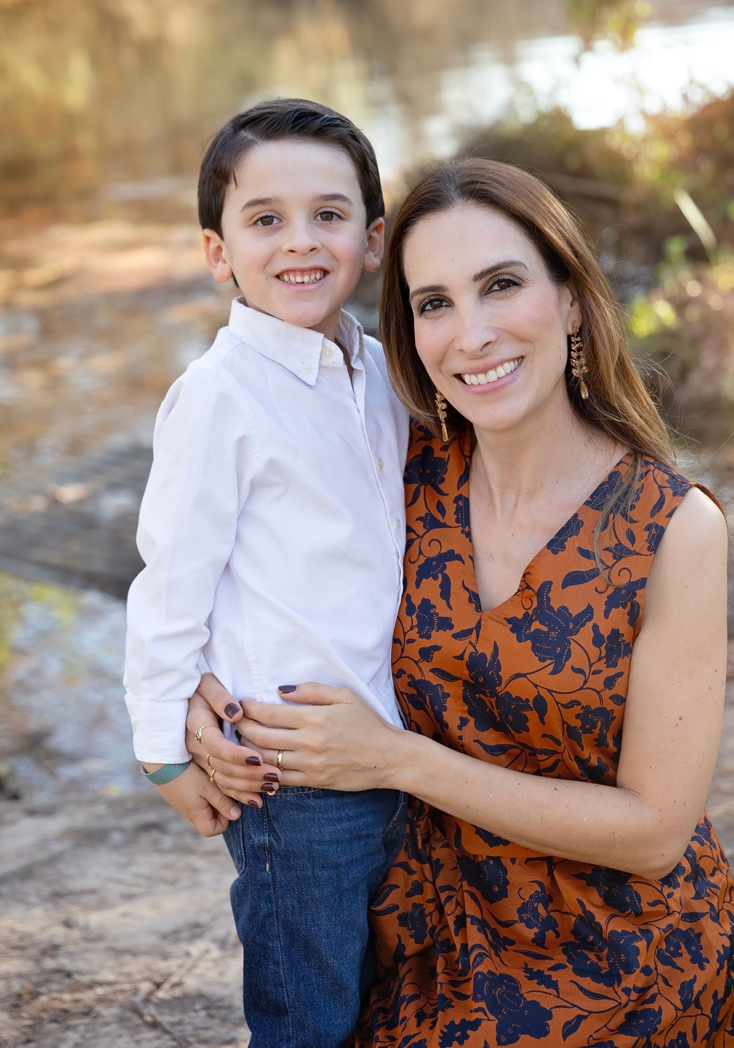 A heartwarming outdoor portrait session featuring a young child in white and an adult in an orange floral dress.