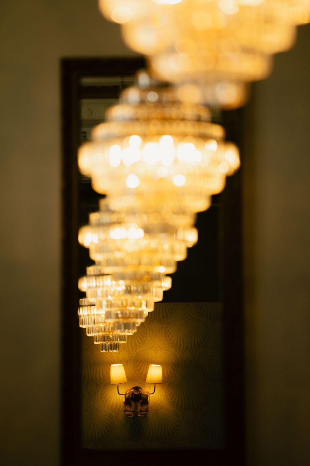 Shoes seen through a mirror along with a line of chandeliers.