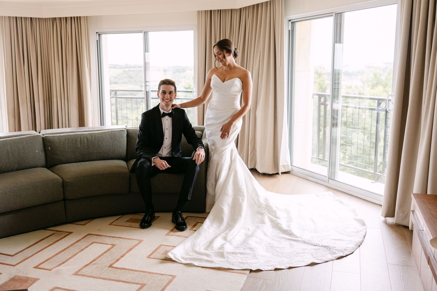 A couple shares romantic moments at an elegant brick building entrance with arched doorways and white columns.