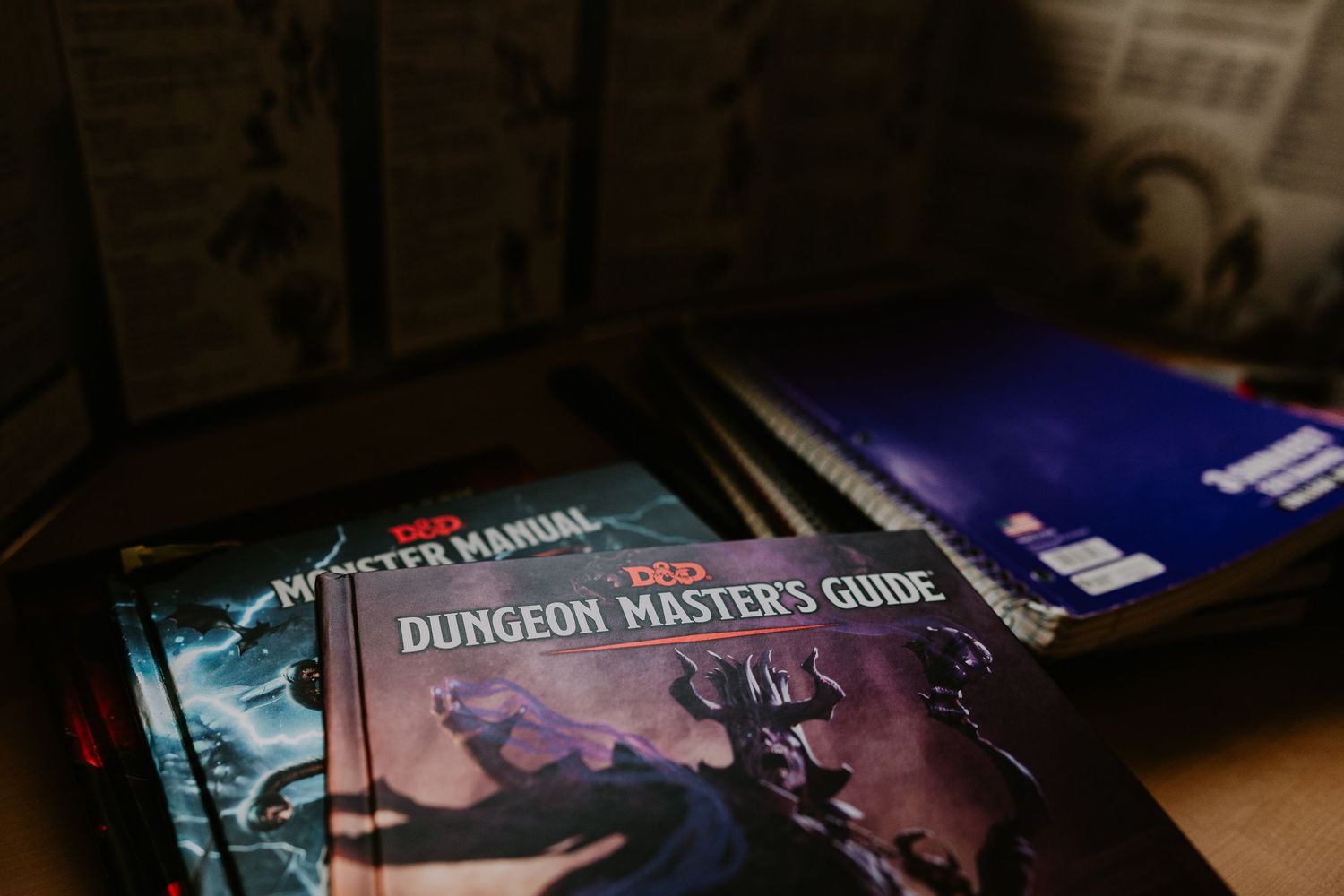 ambient dark notebooks and Dungeon Master's Guide behind a DM screen
