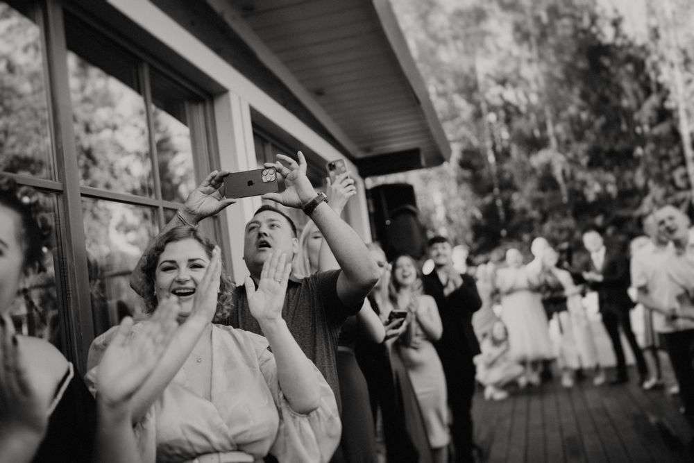 Wedding guests laugh and smile while taking shots during a festive outdoor celebration.