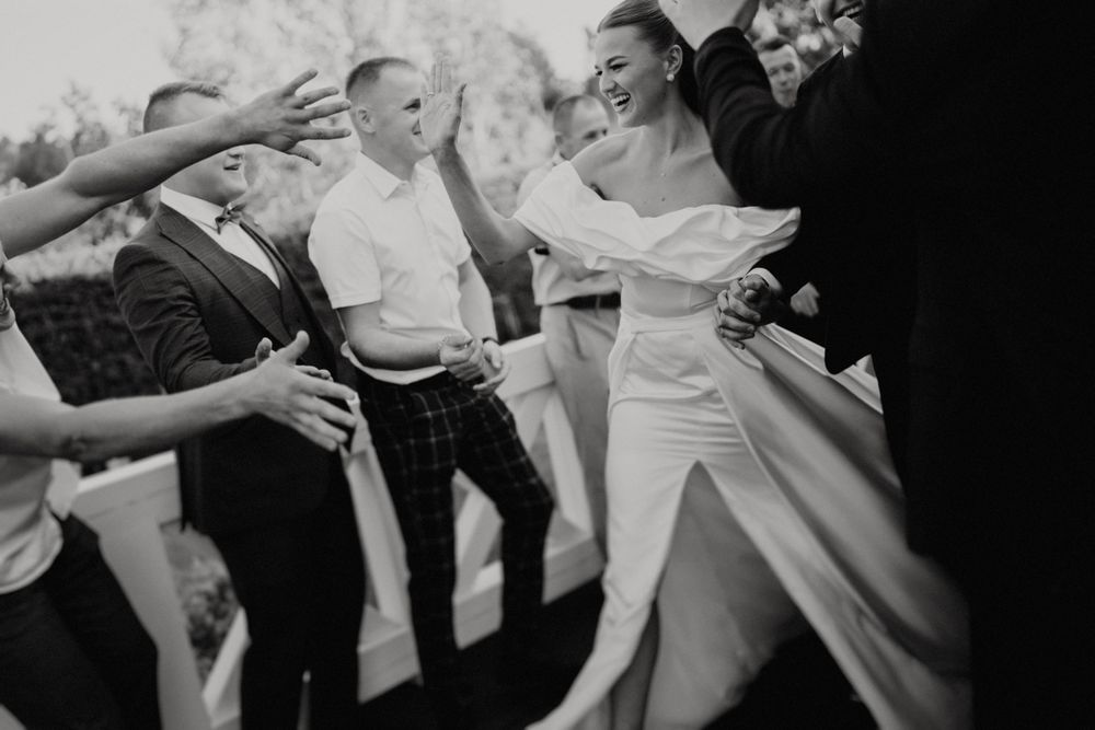 Wedding party members share celebratory drinks at an outdoor reception venue.