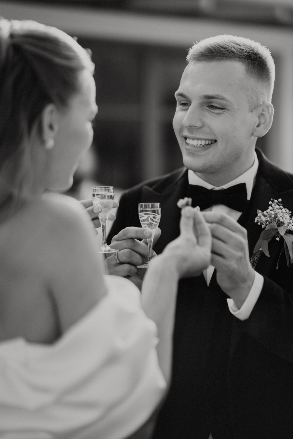 Black and white photo captures joyful moment of wedding party members sharing drinks.
