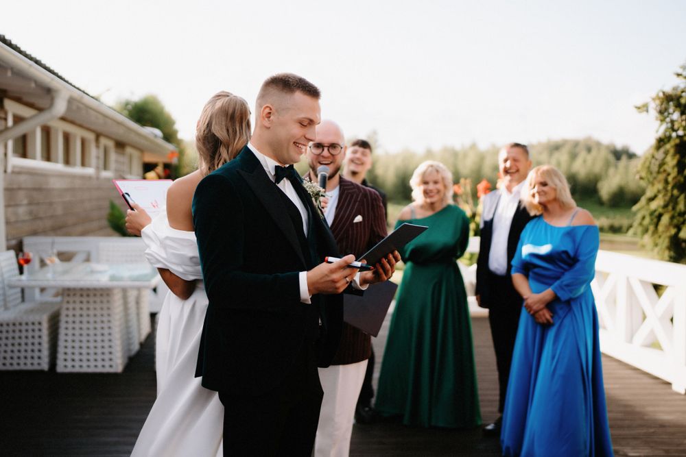 Wedding guests in formal attire gather for drinks at an outdoor reception.