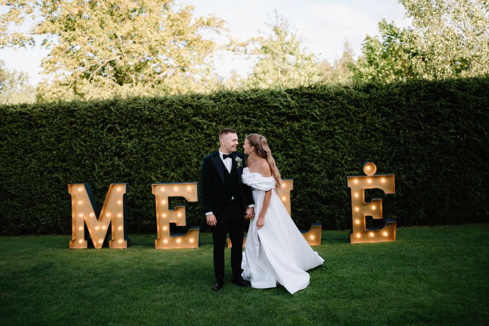 Large illuminated 'LOVE' marquee letters decorate an outdoor wedding reception lawn.