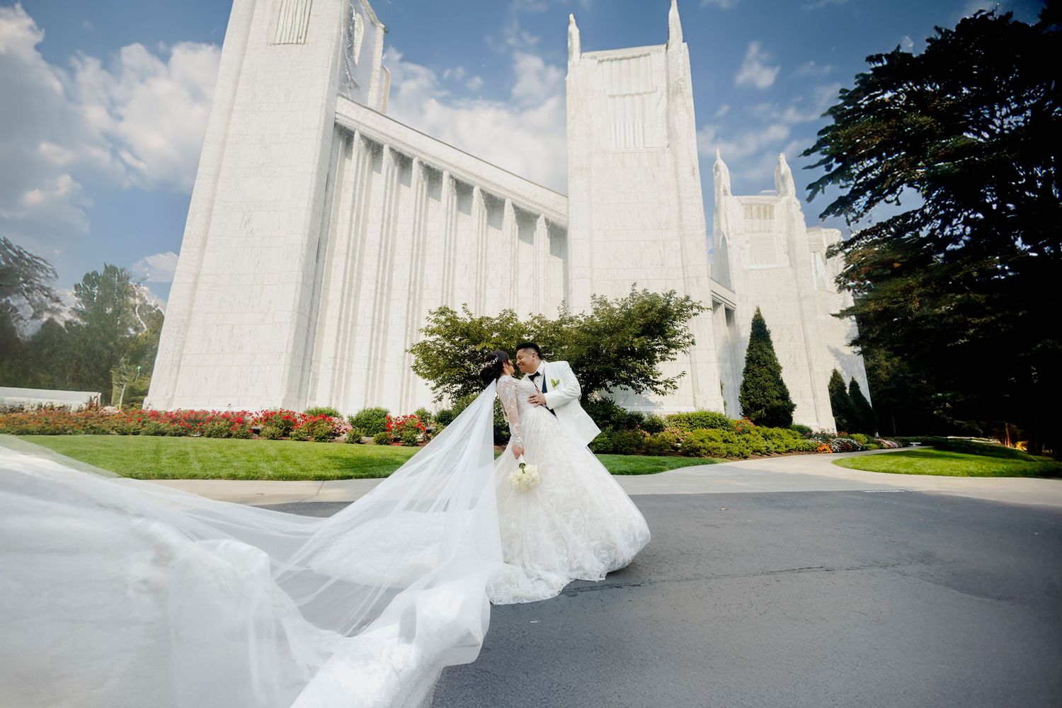 Wedding dress flowing in the breeze against white temple architecture and blue sky.
