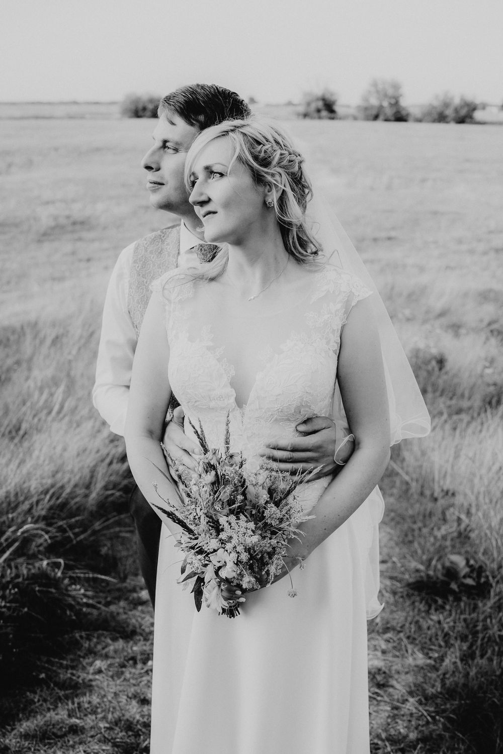 Romantic black and white portrait of newlyweds in a meadow setting.