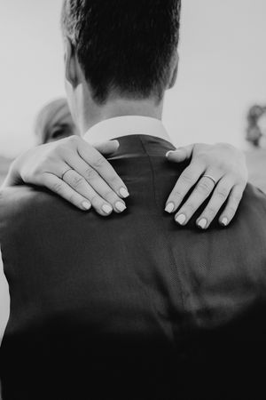 Close-up of hands with wedding rings embracing in black and white.