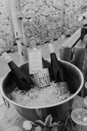 Wine bottles chilling in ice bucket at rustic outdoor wedding reception.