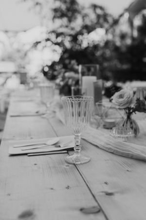 Black and white photo of an elegant table setting with crystal glassware on a rustic wooden table.