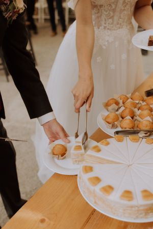 Wedding couple cutting into a white decorated cake at their reception.
