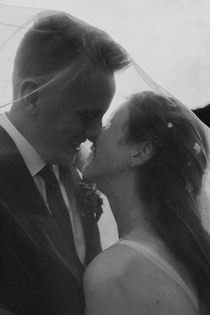 Tender black and white moment between newlyweds sharing an intimate moment under a veil.