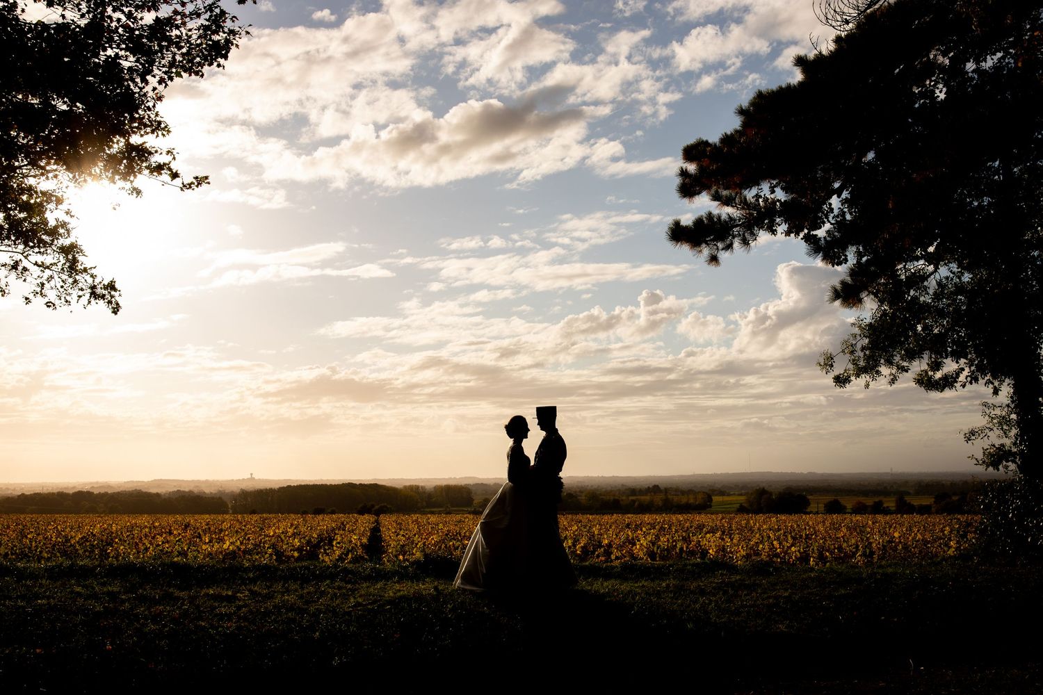couple qui se regarde amoureusement au coucher du soleil devant un champ photographie de mariage
