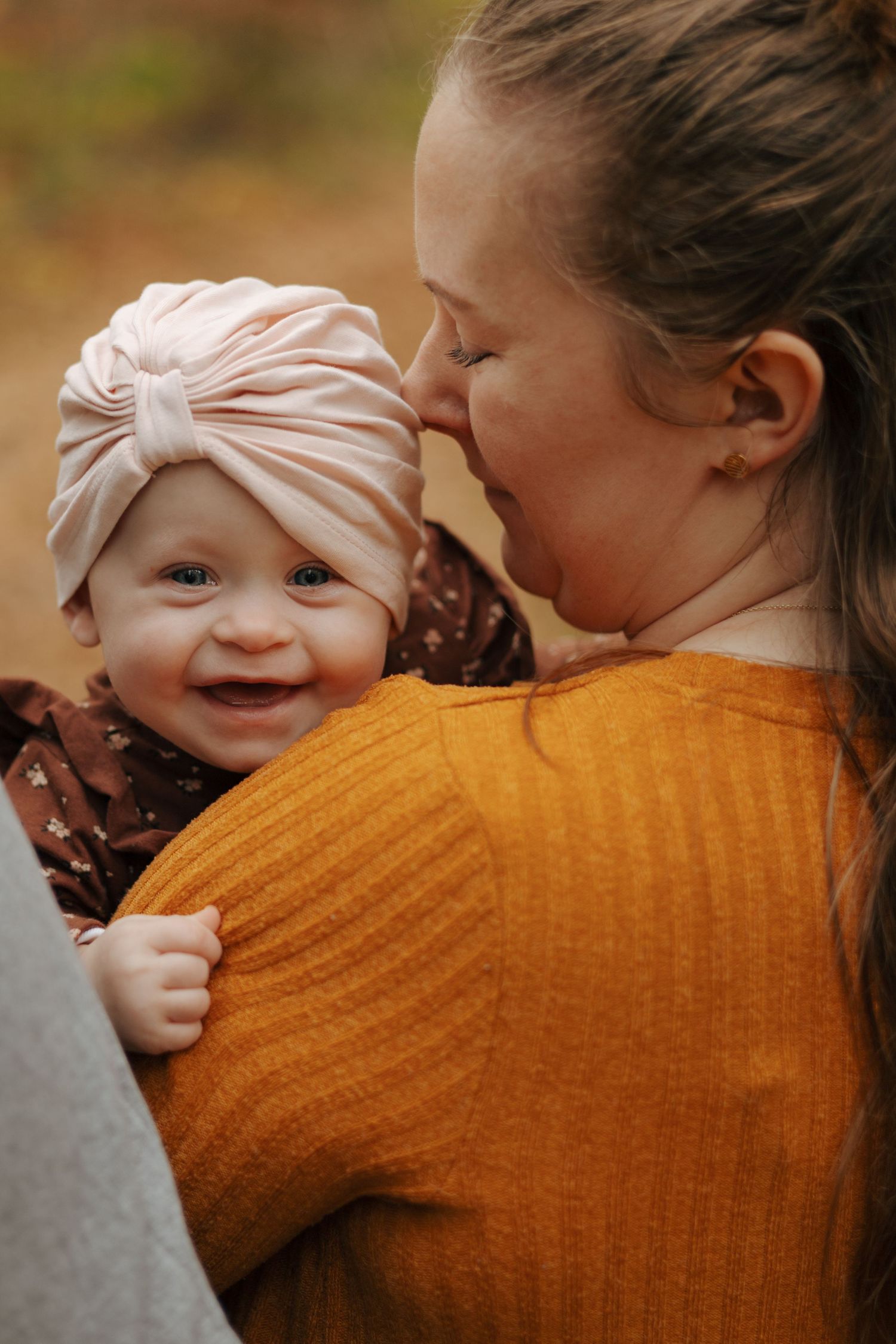 Candid moment of affection between parent and baby against fall colors.