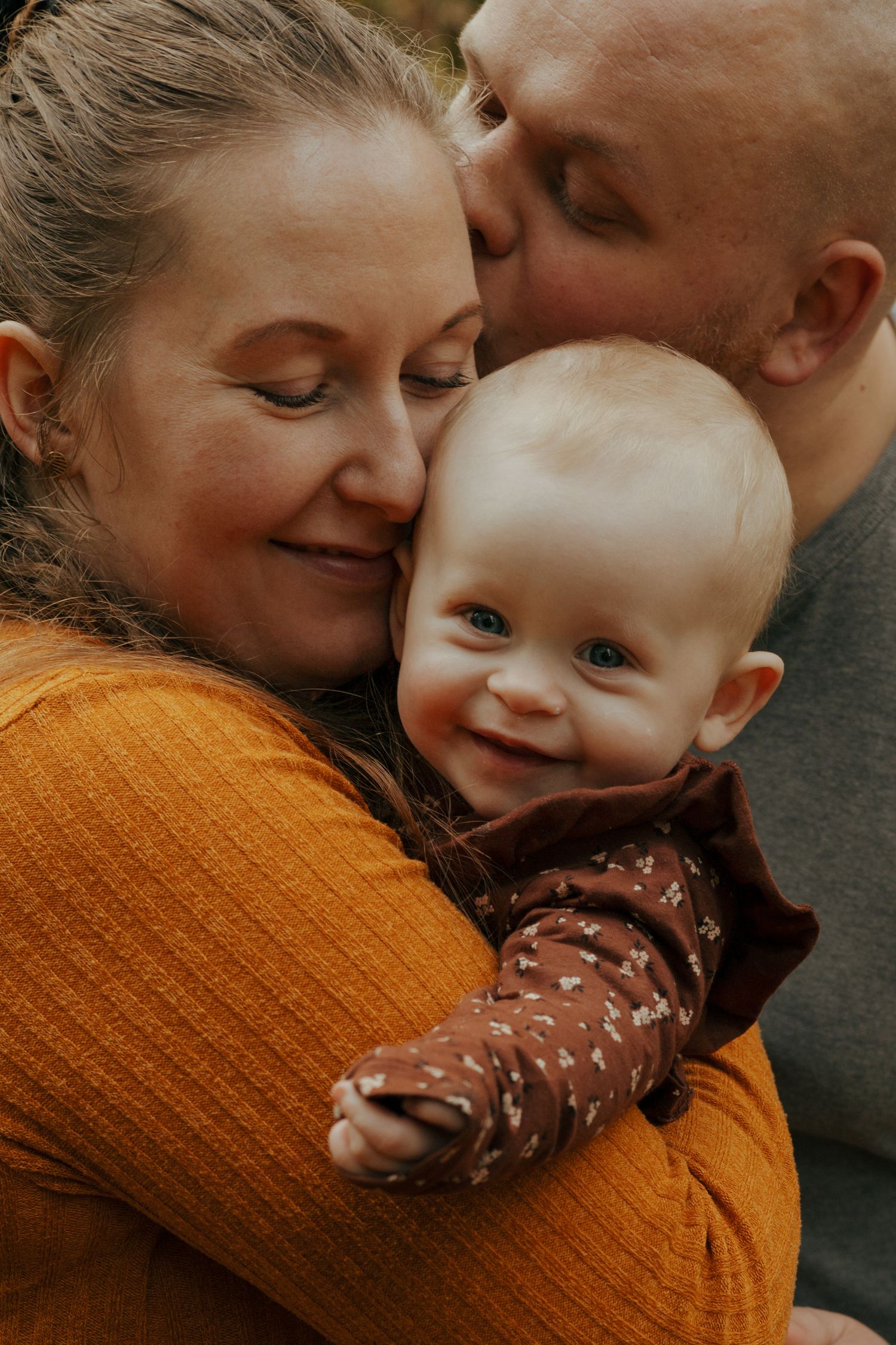 Intimate family moment sharing cuddles against autumn backdrop.