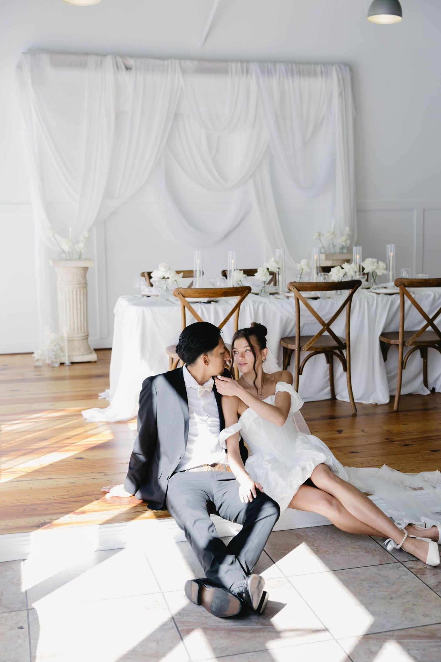 Wedding party celebrates joyfully outdoors wearing light colored suits and dresses.
