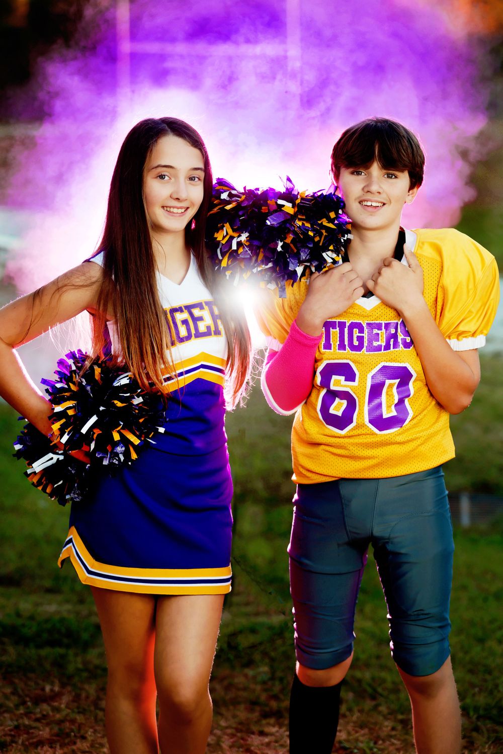 Tigers cheerleader and football player pose together with purple smoke effect background.