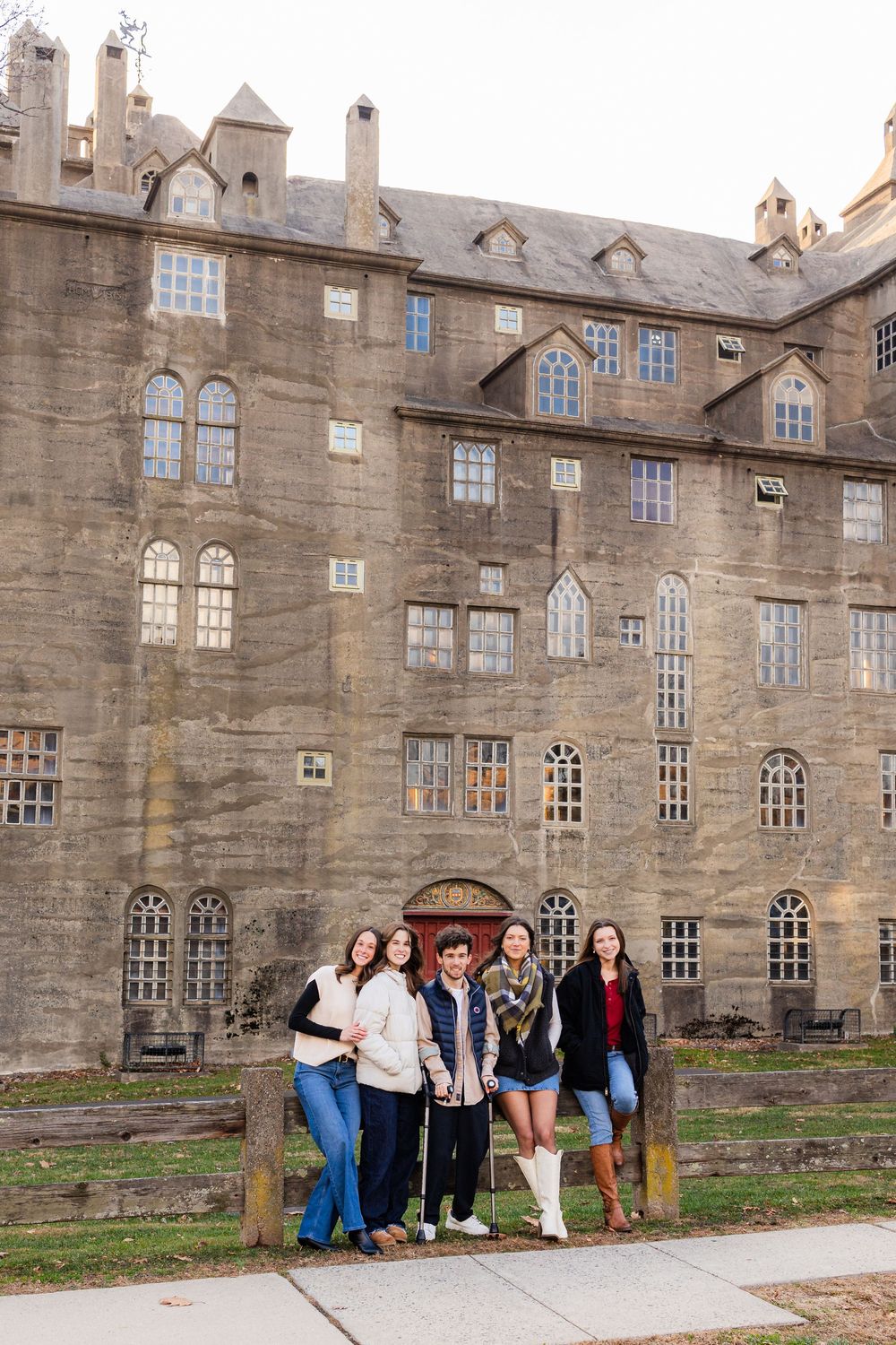Five friends pose together in front of a large historic stone building with arched windows.