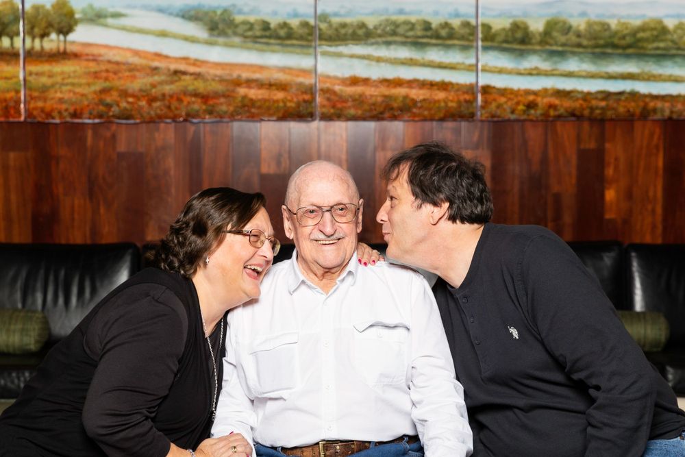 Indoor family moment on a leather couch with a landscape painting in the background.