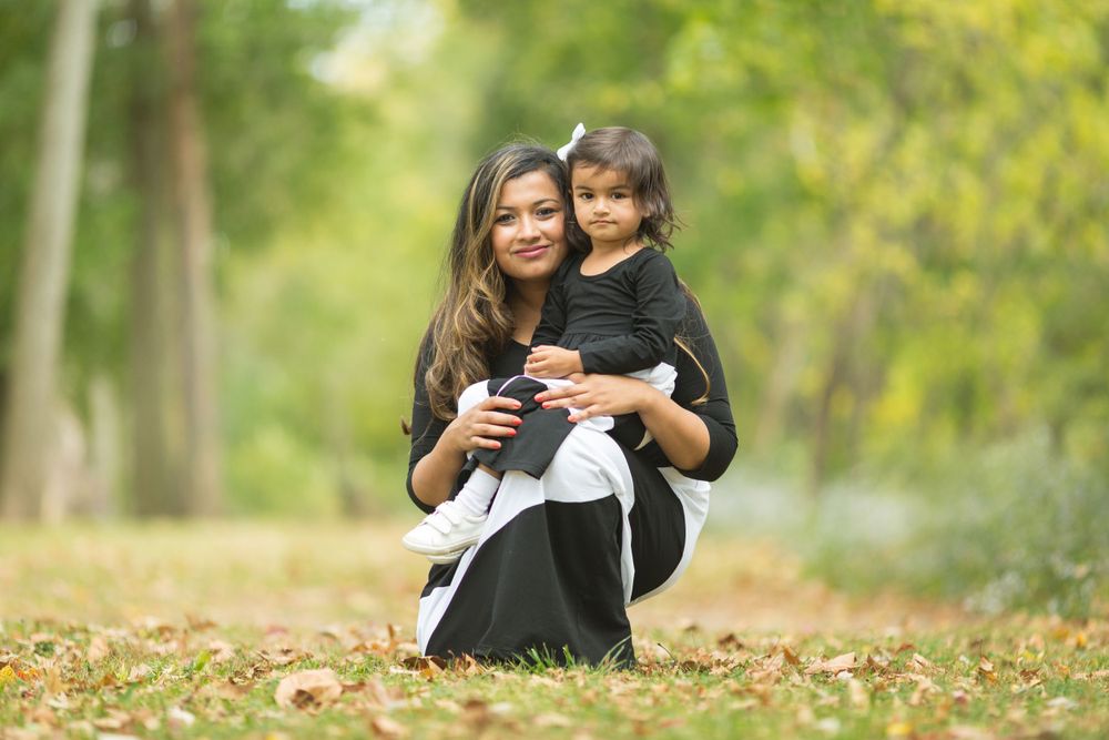Two people share a happy moment together in an autumn park with fallen leaves on the ground.