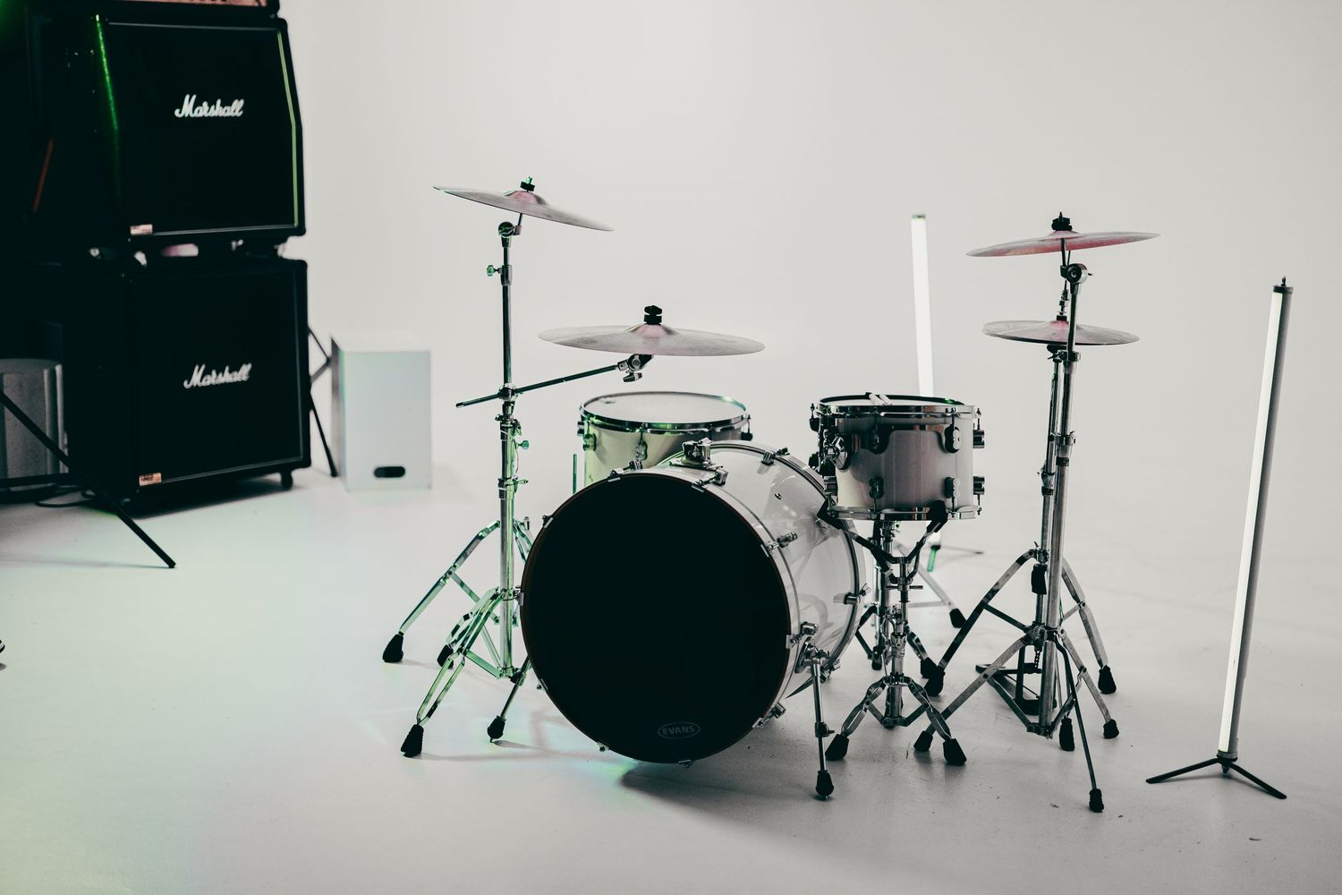 Professional drum kit setup with Marshall amp against white studio backdrop.