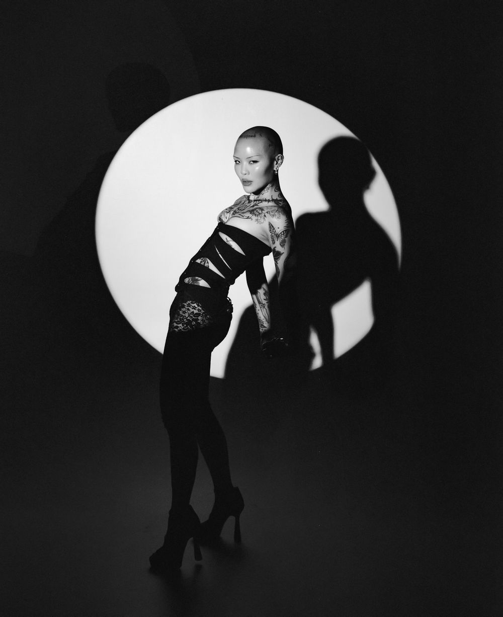 Black and white portrait with circular spotlight highlighting model in elegant pose.