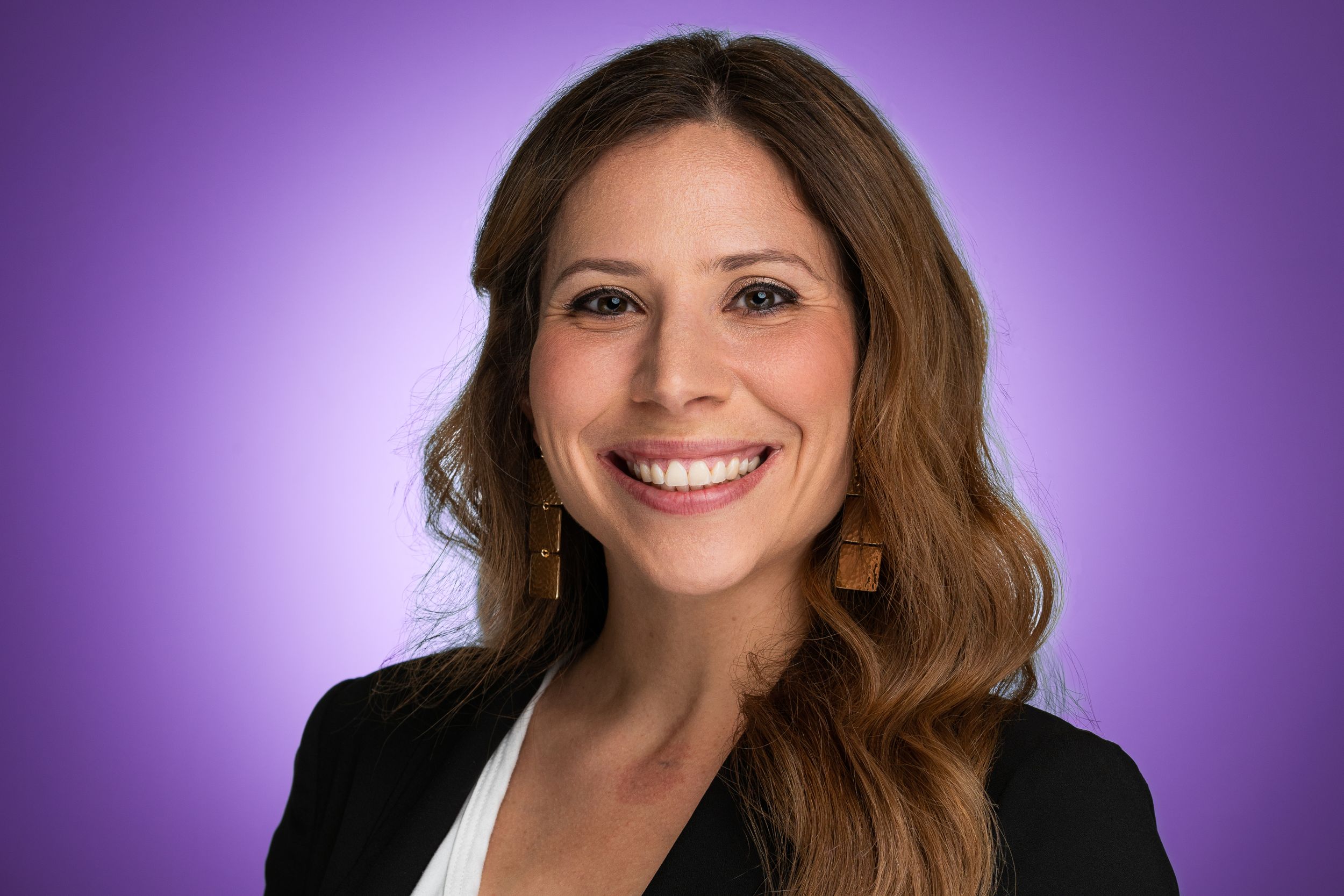 Professional headshot of someone in business attire against a purple background.