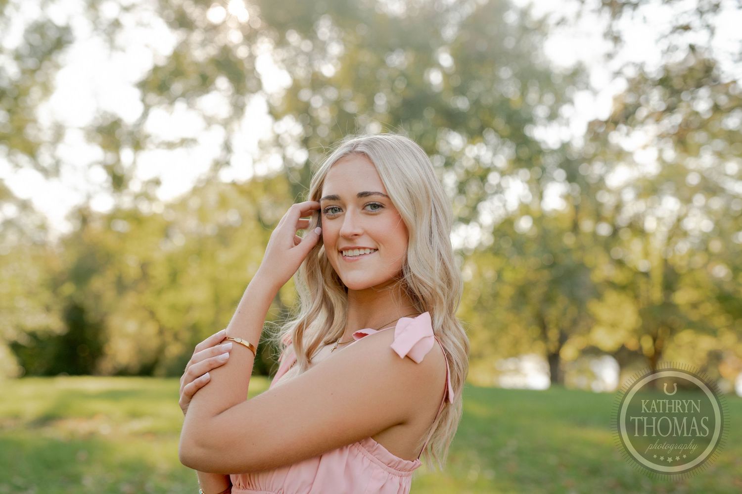 A joyful outdoor portrait with soft natural lighting and green trees in the background.