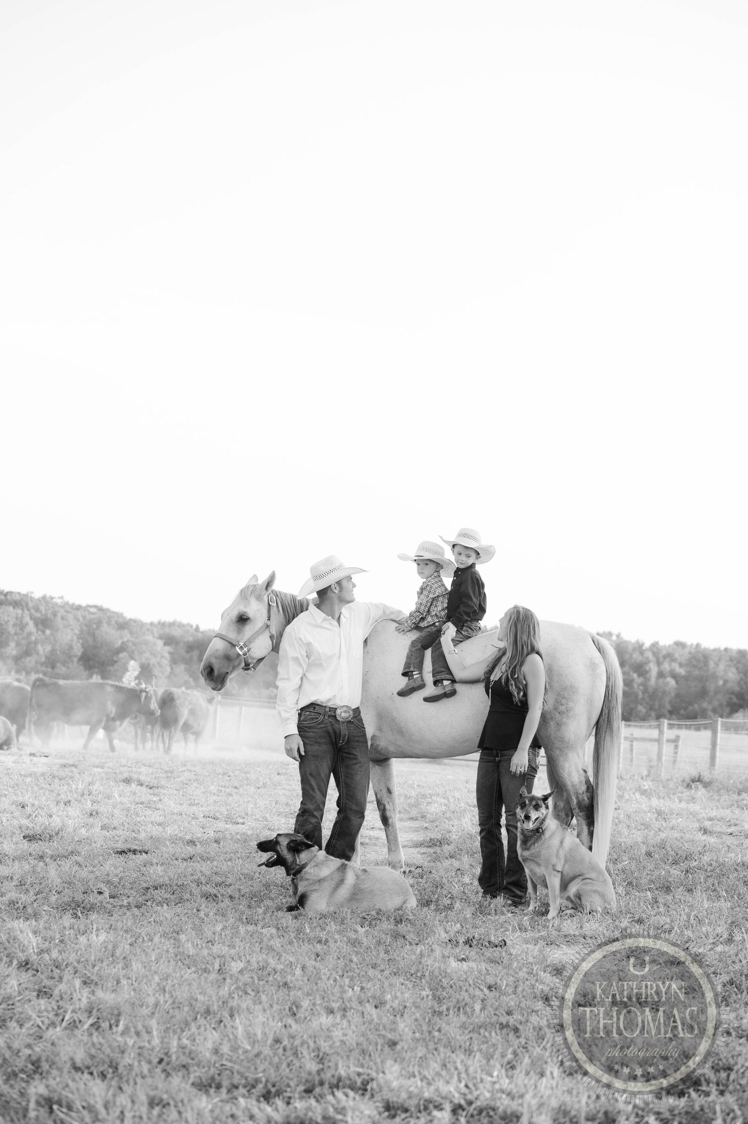Black and white photo of a child on horseback with adults in a rural setting.